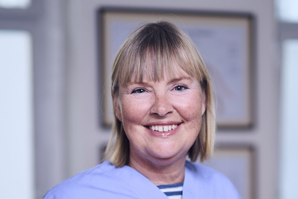 Porträt einer lächelnden Mitarbeiterin einer Tierarztpraxis in Arbeitskleidung