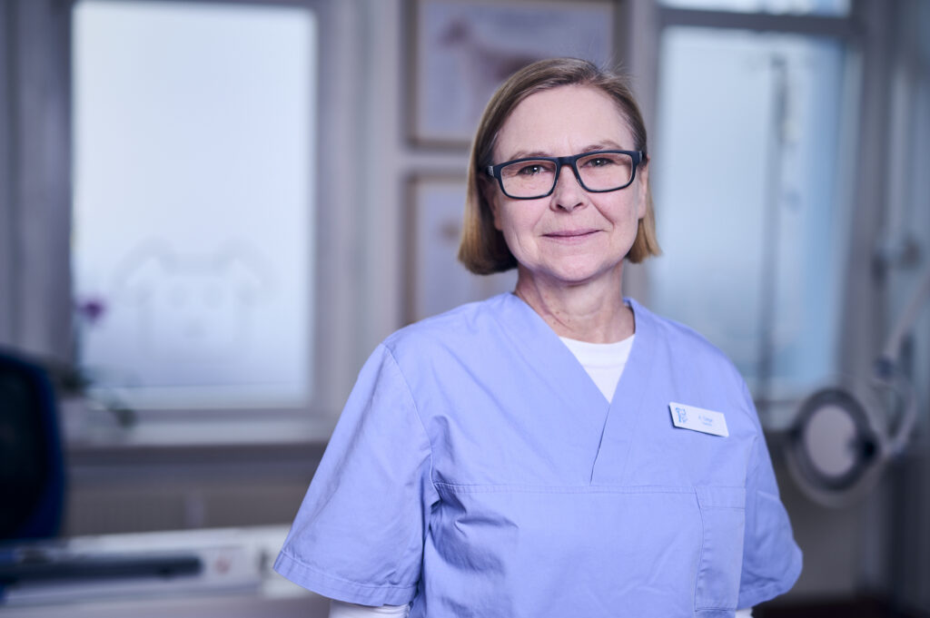 Porträt einer lächelnden Mitarbeiterin einer Tierarztpraxis in Arbeitskleidung