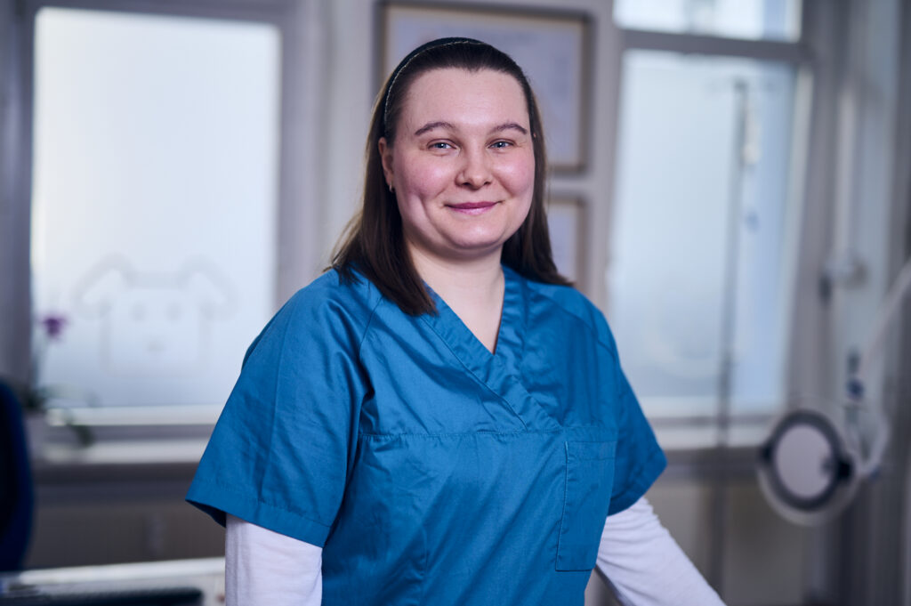 Porträt einer lächelnden Mitarbeiterin einer Tierarztpraxis in Arbeitskleidung