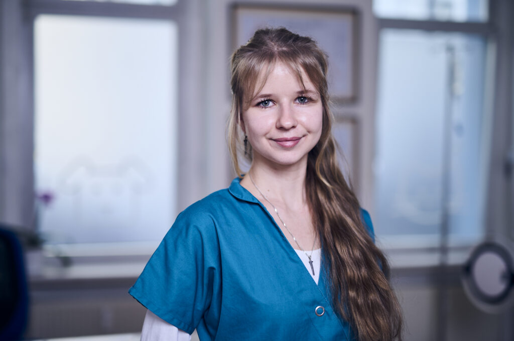 Porträt einer lächelnden Mitarbeiterin einer Tierarztpraxis in Arbeitskleidung