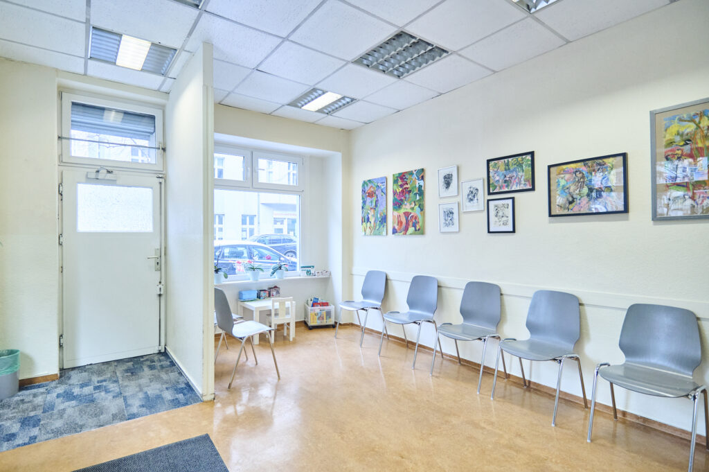 Wartezimmer einer Tierarztpraxis mit mehreren Stühlen, Kinderbereich, Fenstern und bunten Bildern an der Wand.