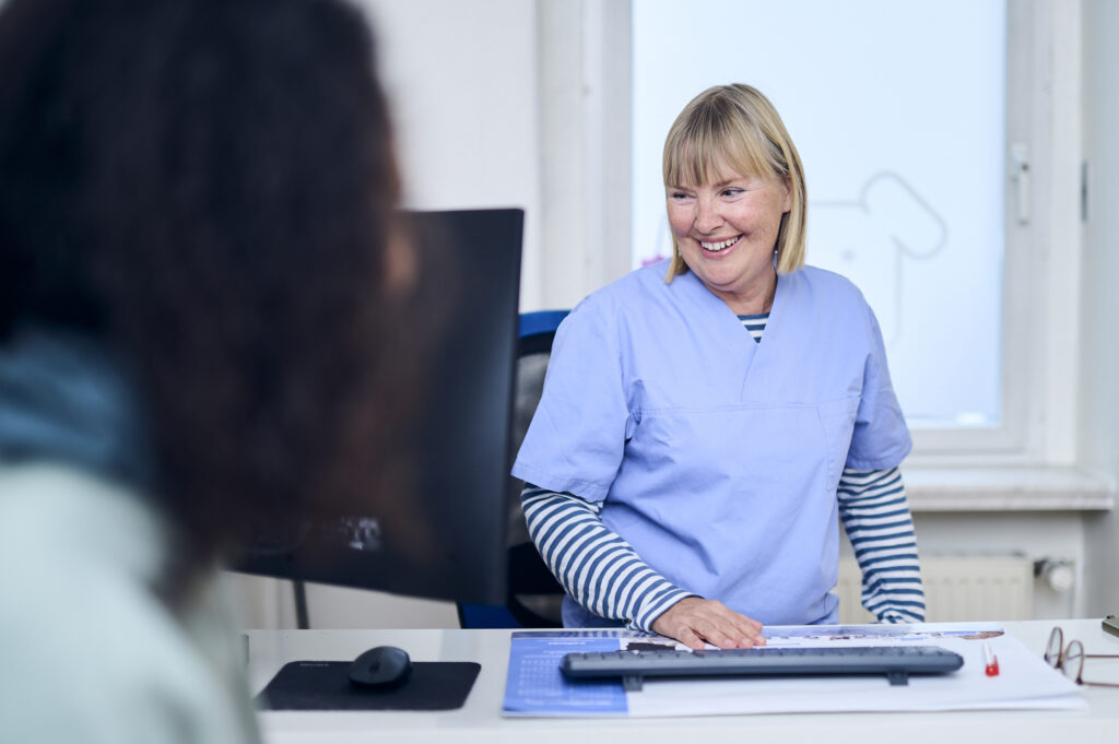 Mitarbeiterin am Empfang einer Tierarztpraxis im Gespräch mit einer Kundin.